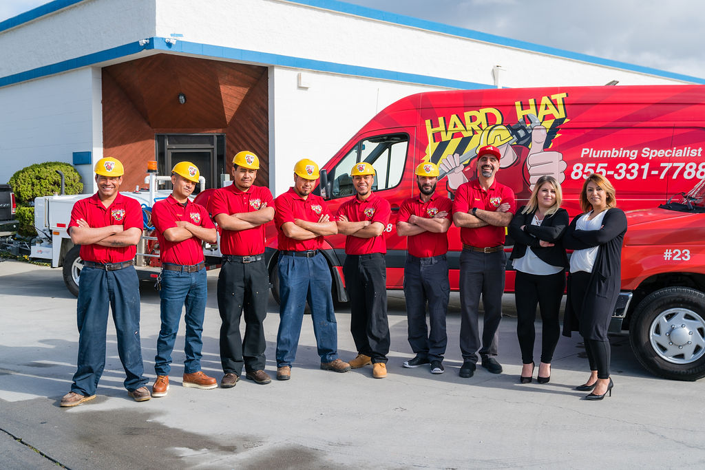 Hard Hat Rooter and Plumbing team in front of the company vans