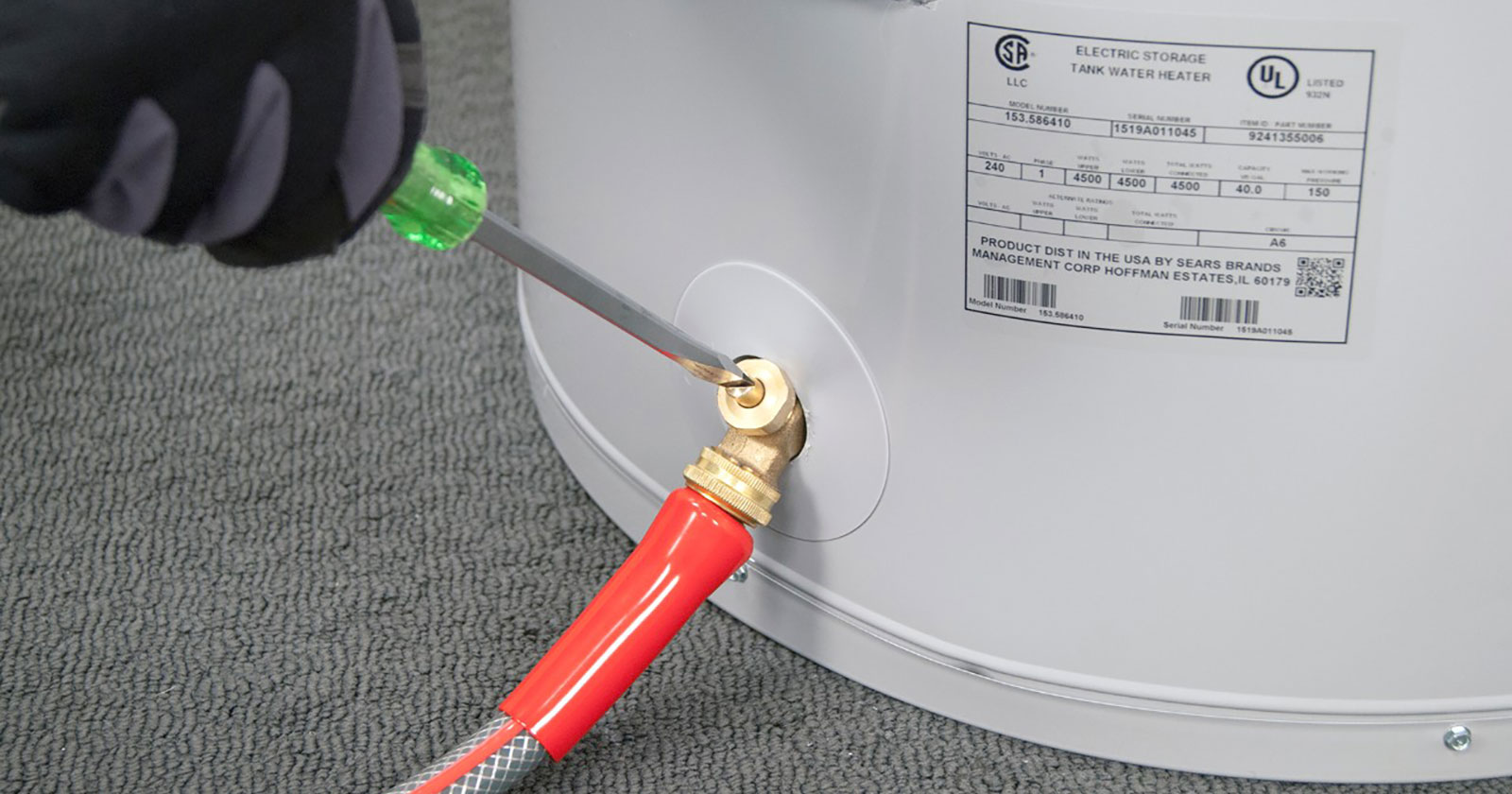 Garden hose connected to the drain valve at the bottom of a tank water heater